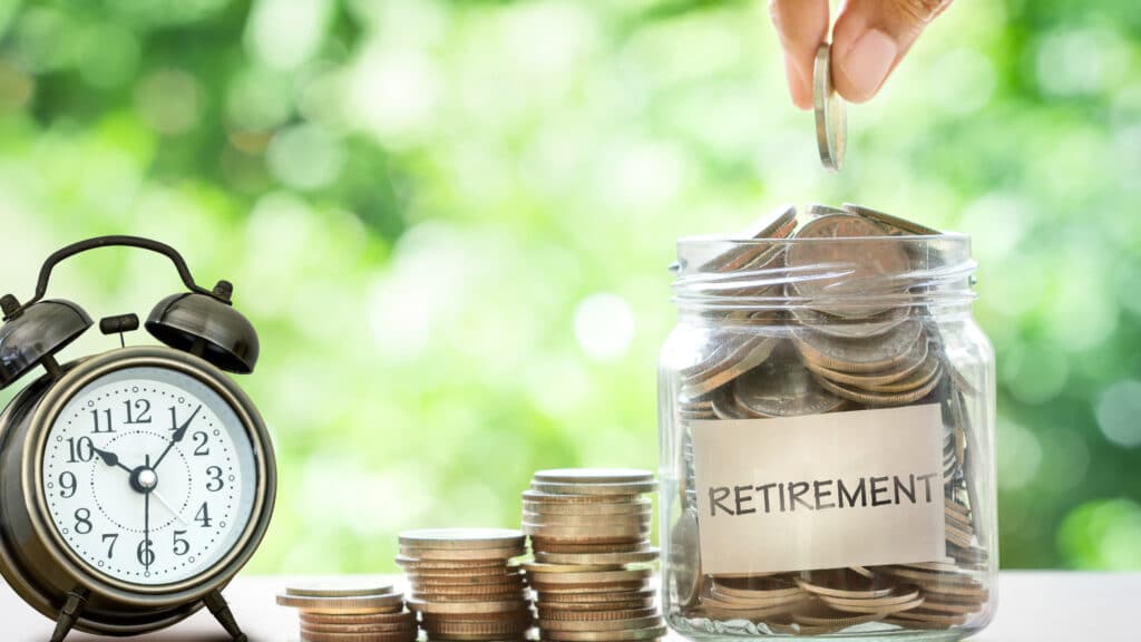 Person putting money into a retirement savings jar.